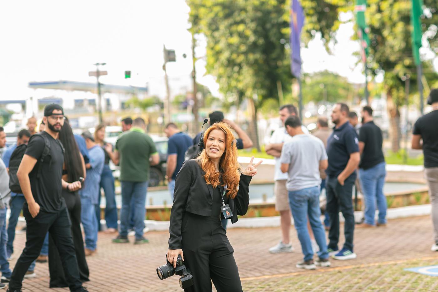 Fotógrafa da equipe com câmera e headset durante evento ao ar livre