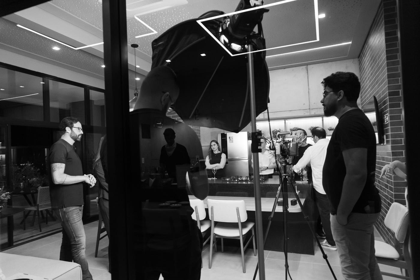 Set em apartamento decorado com softbox, câmera no tripé e equipe acompanhando a gravação